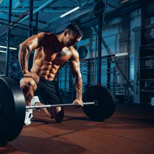 Portrait of muscled athlete, bodybuilder workouts alone at sport gym, indoors.